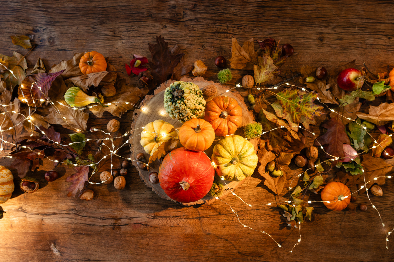 Directly above view of an oak table decorated for a delightful thanksgiving evening, the table is adorned with twinkling fairy lights and rustic pumpkins in a restaurant in Newcastle, England.