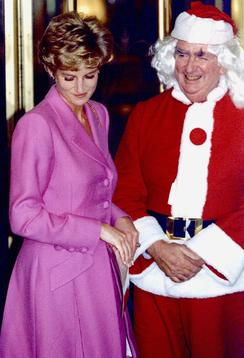 The Princess of Wales and Lord Healey dressed in a Santa Claus costume smile as they leave a lunch f..