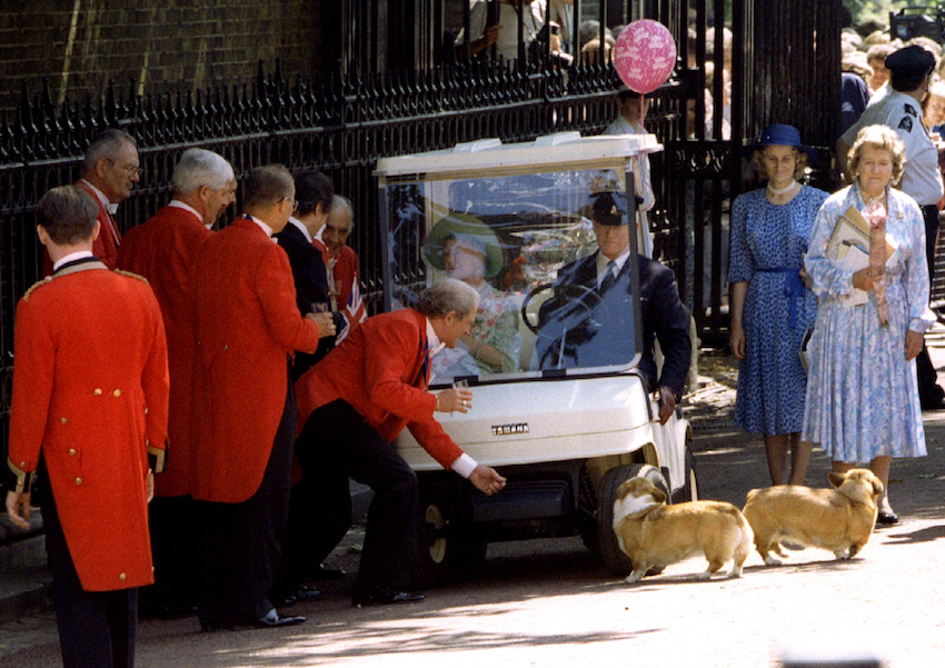 The Queen Mother passes wellwishers in her golf buggy August 4 as attendants usher her royal corgis...