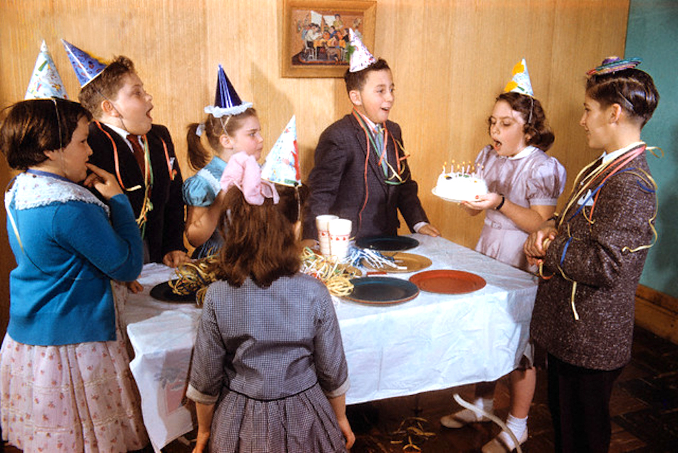 Children Watching Girl Blow Out Birthday Candles