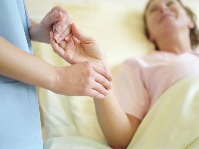 Nurse checking female patient's pulse on wrist, close-up