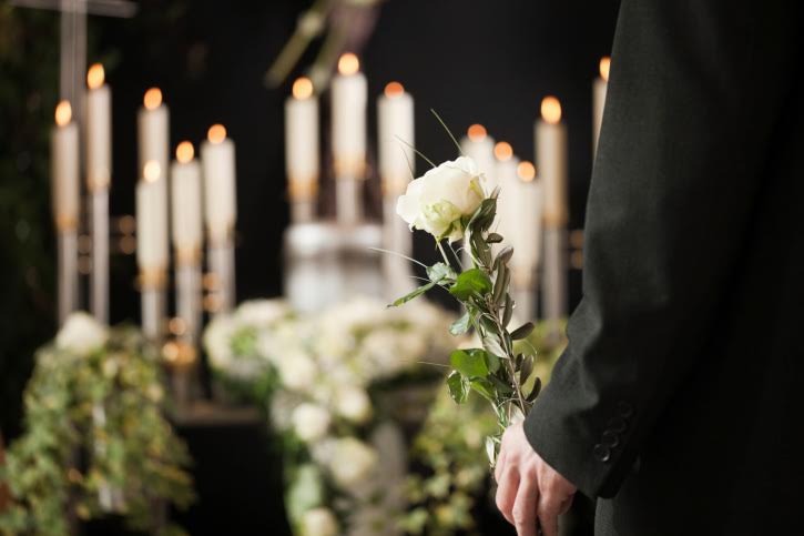 Grief - man with white roses at urn funeral