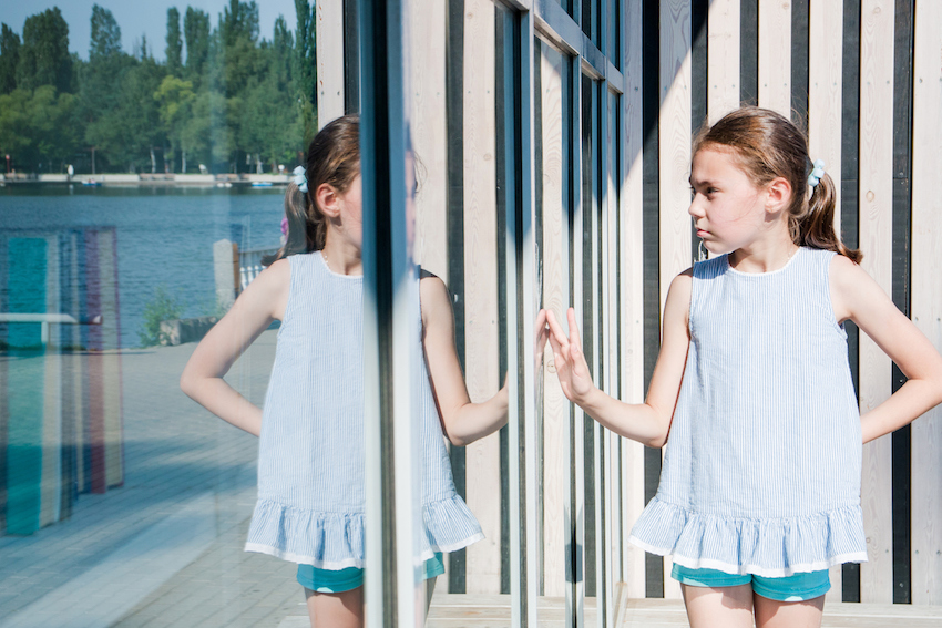 small cute girl looks at her reflection sunny day