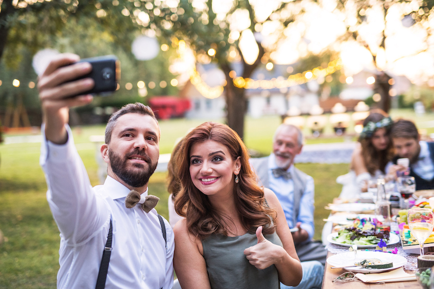 A couple taking selfie at the wedding reception outside in the backyard.