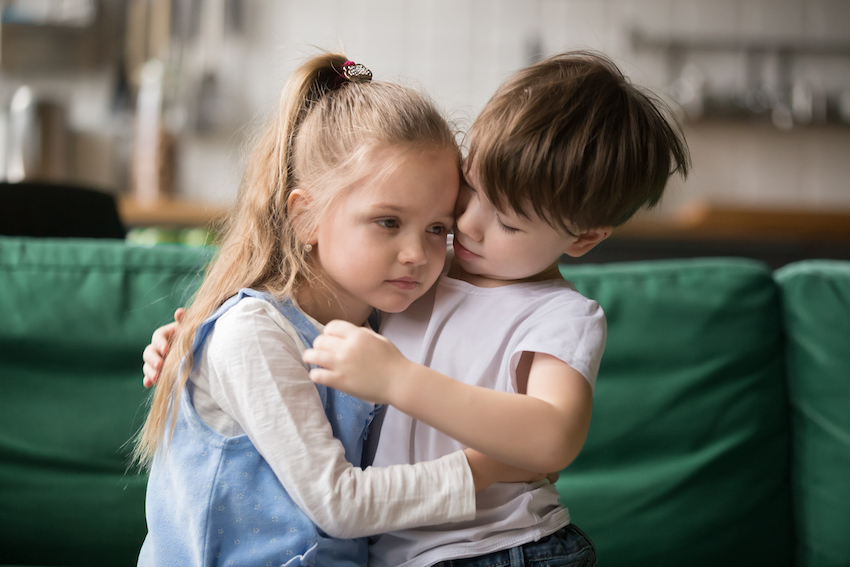 Little boy brother consoling and supporting upset girl embracing sister