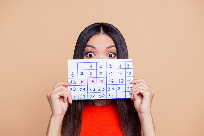 Close up photo portrait of terrified amazed with big eyes lady closing covering she face with paper handmade calendar isolated on pastel beige background copy space