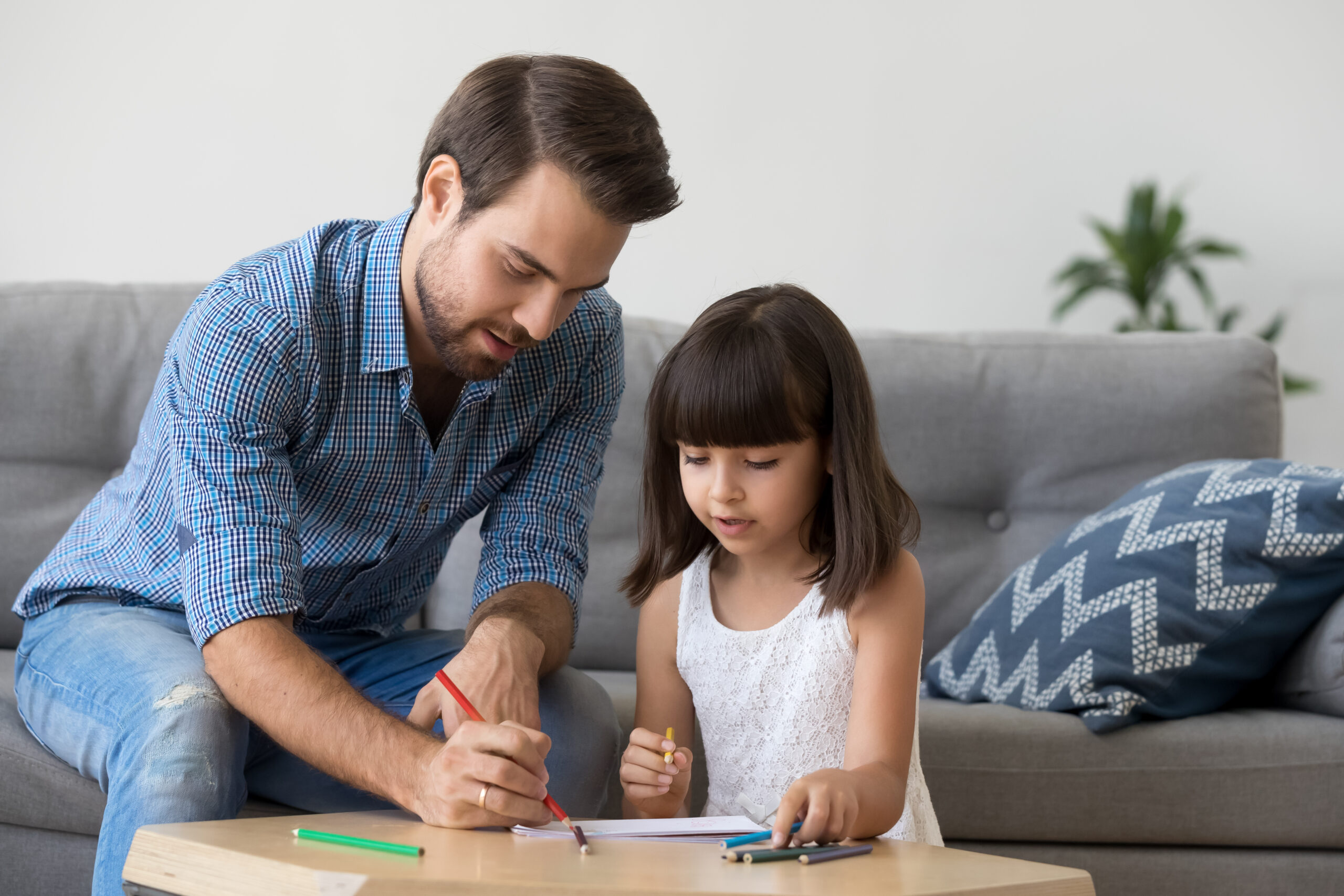 Dad and preschool kid girl drawing with colored pencils together