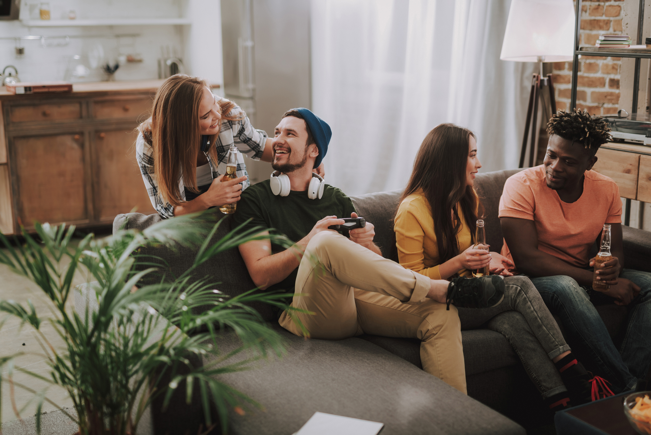 Friends chatting, playing video games and enjoying drinks at home