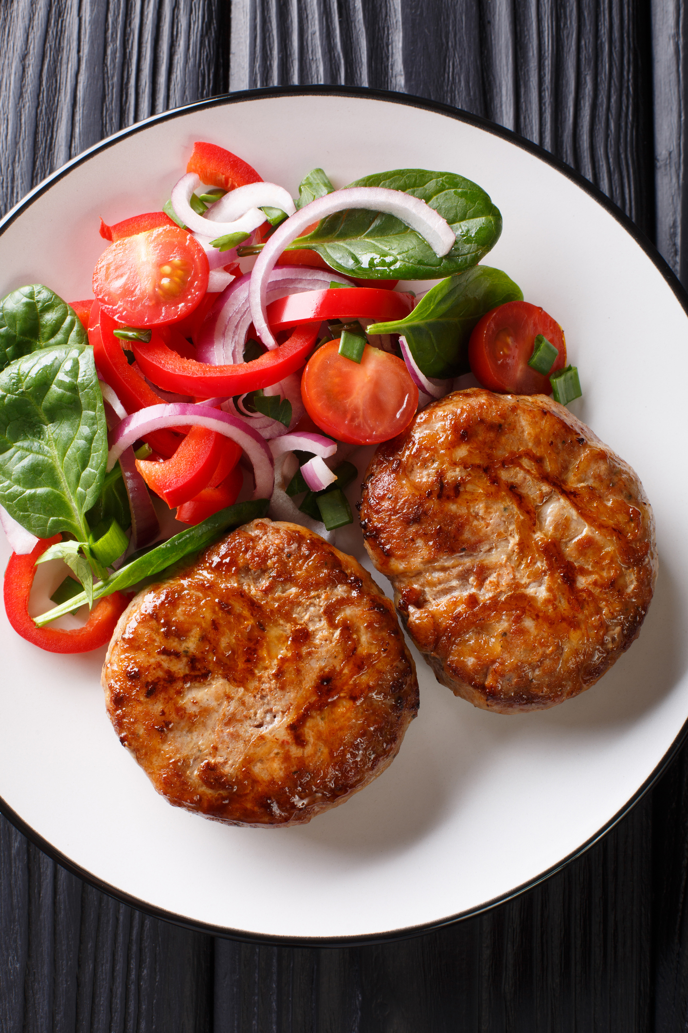 Natural French fried meat balls crepinette and fresh vegetable salad close-up on a plate. Vertical top view