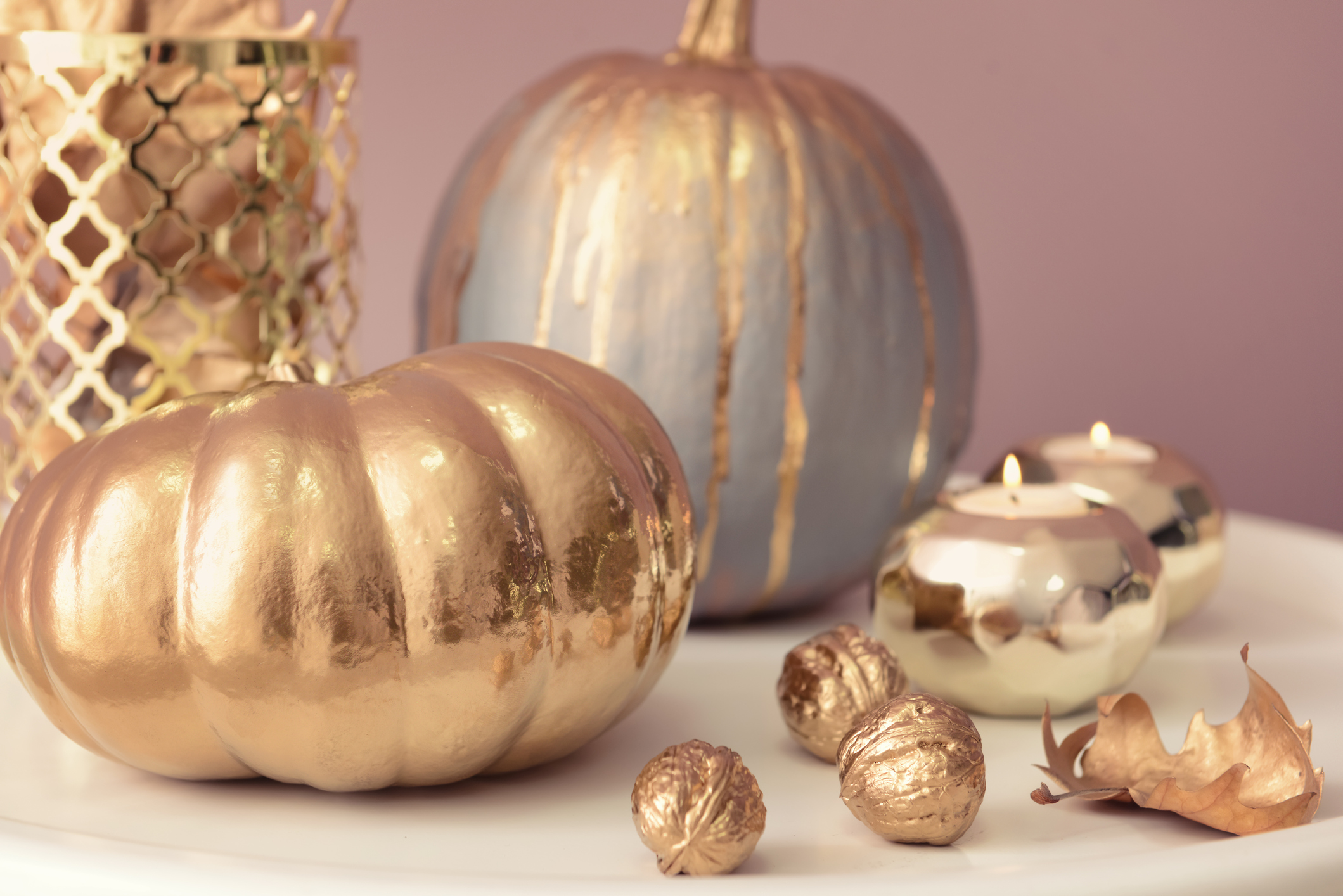 Painted pumpkins with candles on white table