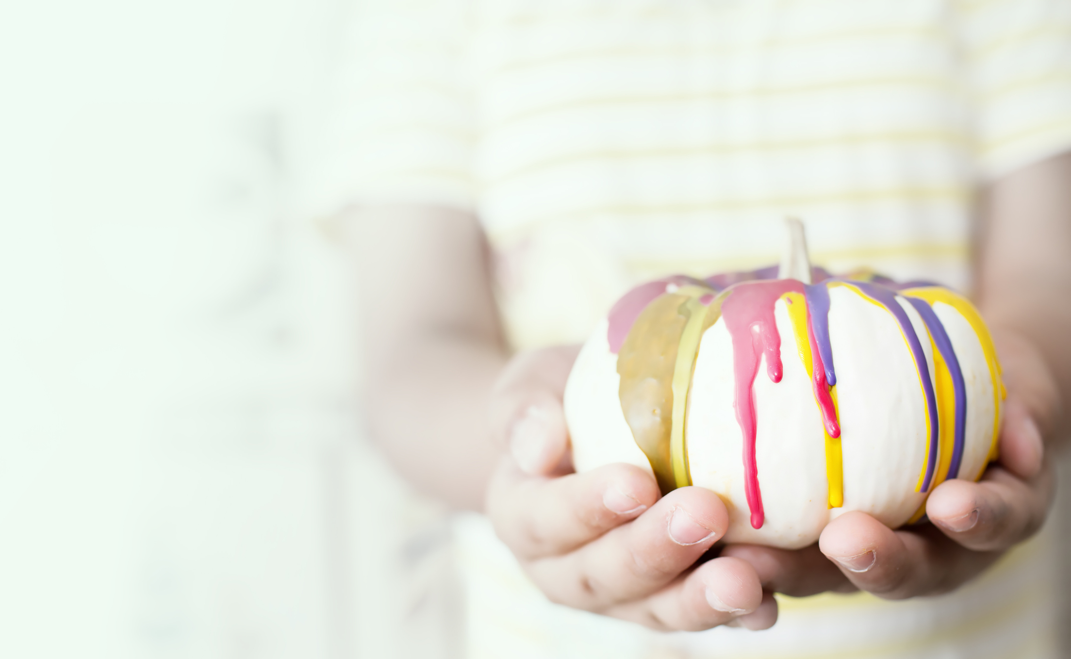 Soft focus of Asian young girl with colorful pumpkin in hand.