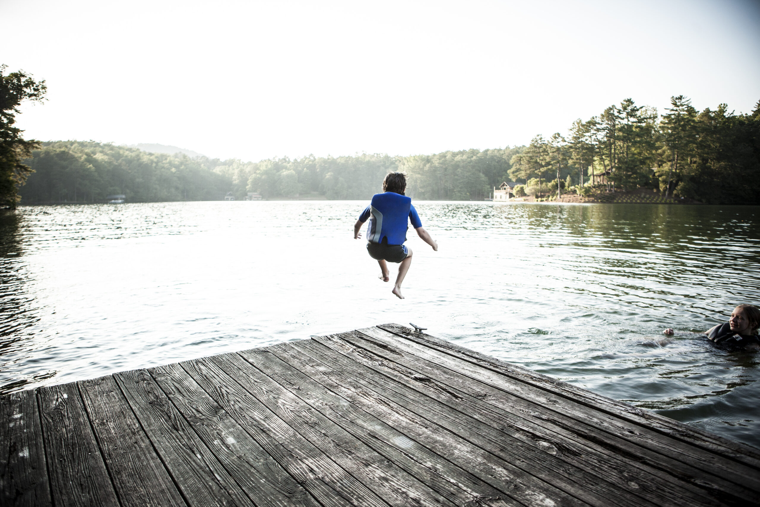 boy jumping off dock into lake