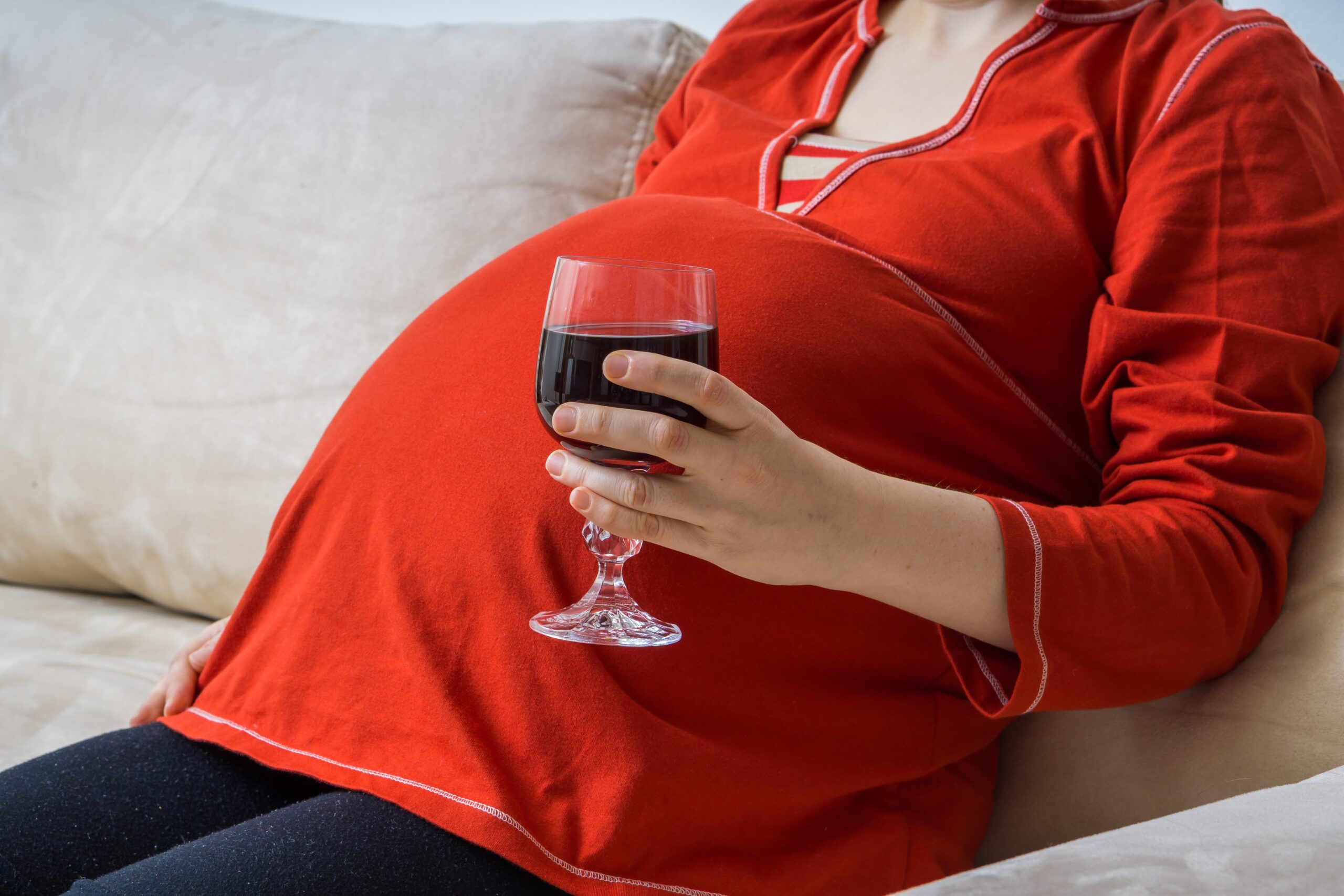 Drinking alcohol in pregnancy. Pregnant alcoholic woman is drinking wine.
