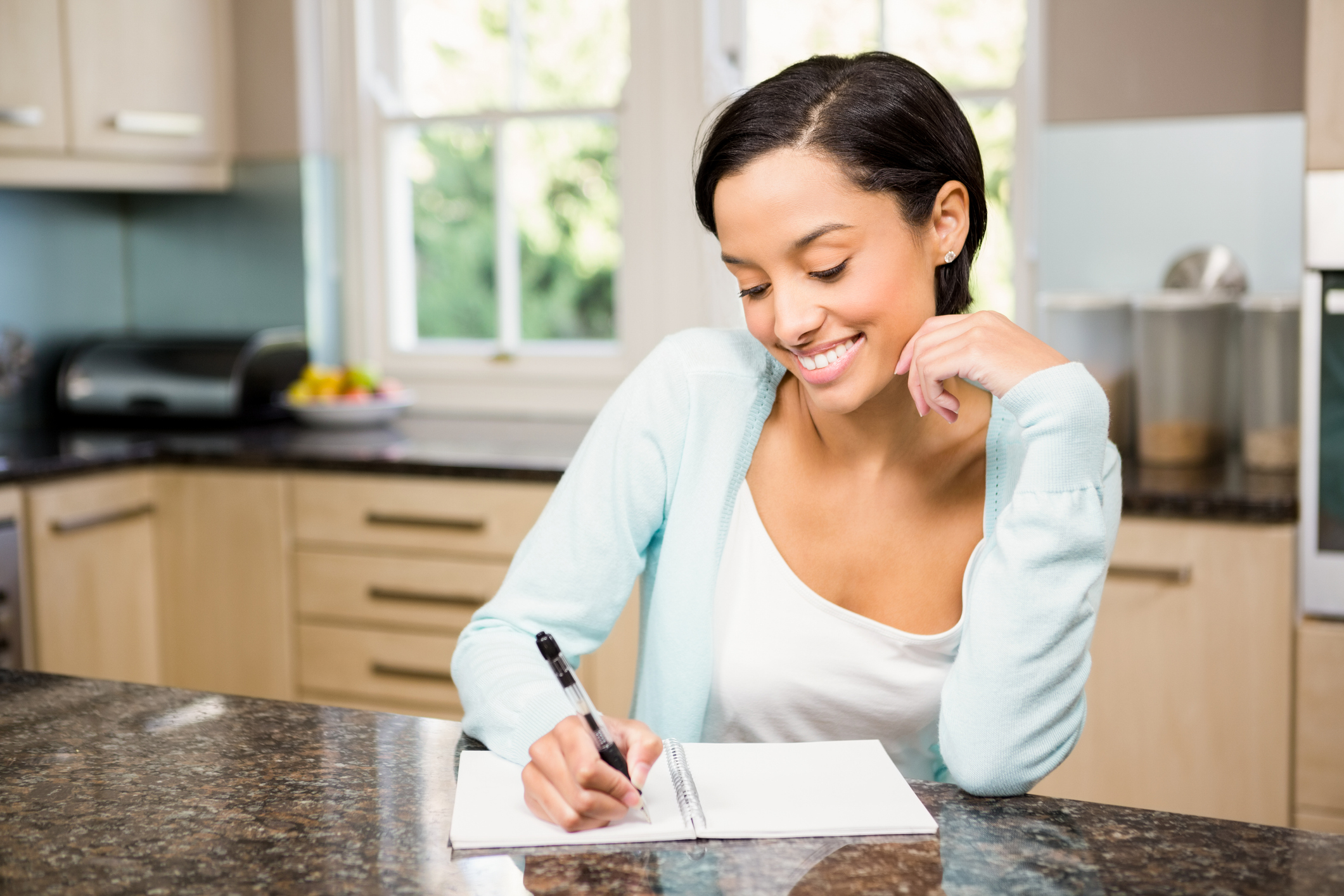 Smiling brunette writing on note pad