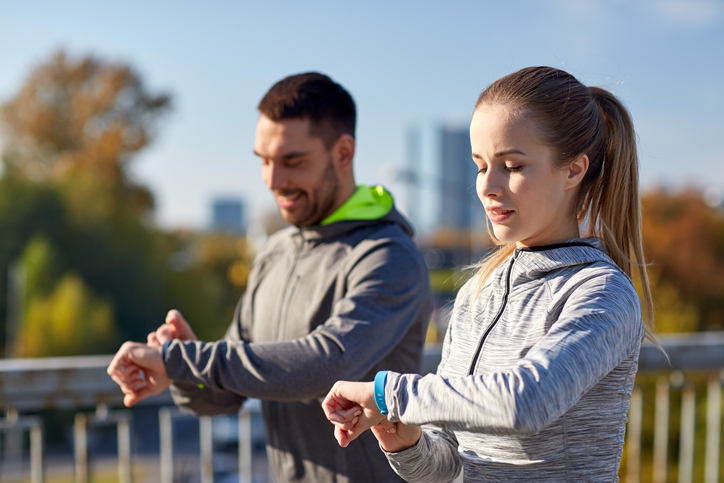 couple with fitness trackers training in city