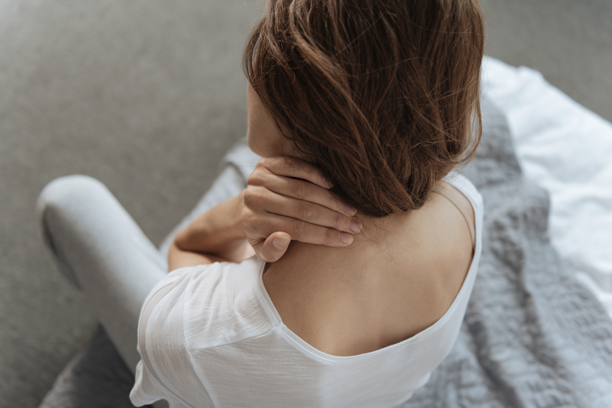 Unhappy young woman suffering from pain in the neck