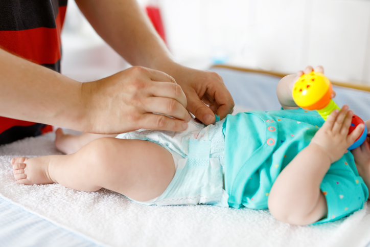 Close-up of father changing diaper of his newborn baby daughter.