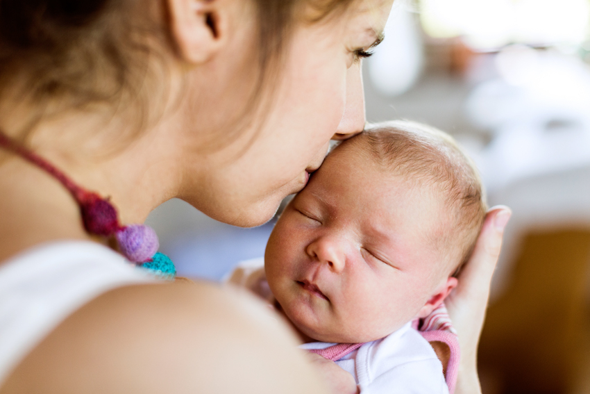 Young mother at home holding her newborn baby daughter