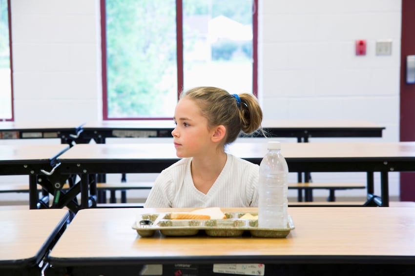 Student sitting with lunch tray and bottle of water