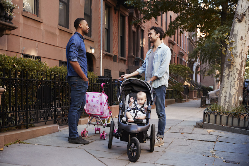 Two father friends with two kids talking in the street