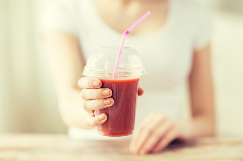 close up of woman holding cup with smoothie
