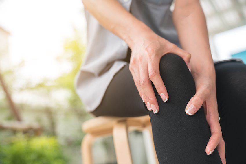 A young woman massaging her painful knee