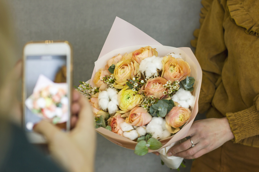 Girl shoots on your smartphone beautiful rustic bouquet in the friend's hands