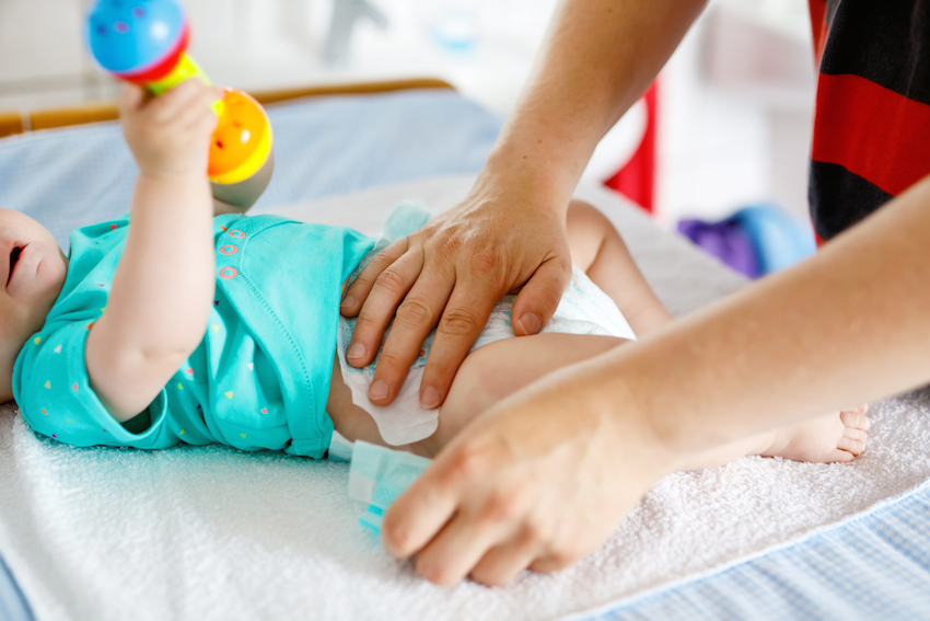 Close-up of father changing diaper of his newborn baby daughter.