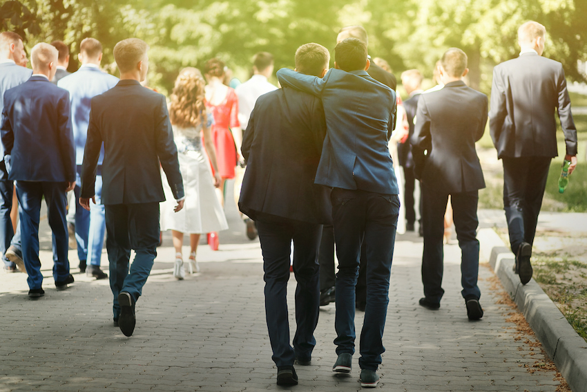 stylish confident man in suit having fun, group of people walking, reception at luxury wedding, rich graduation at school or university