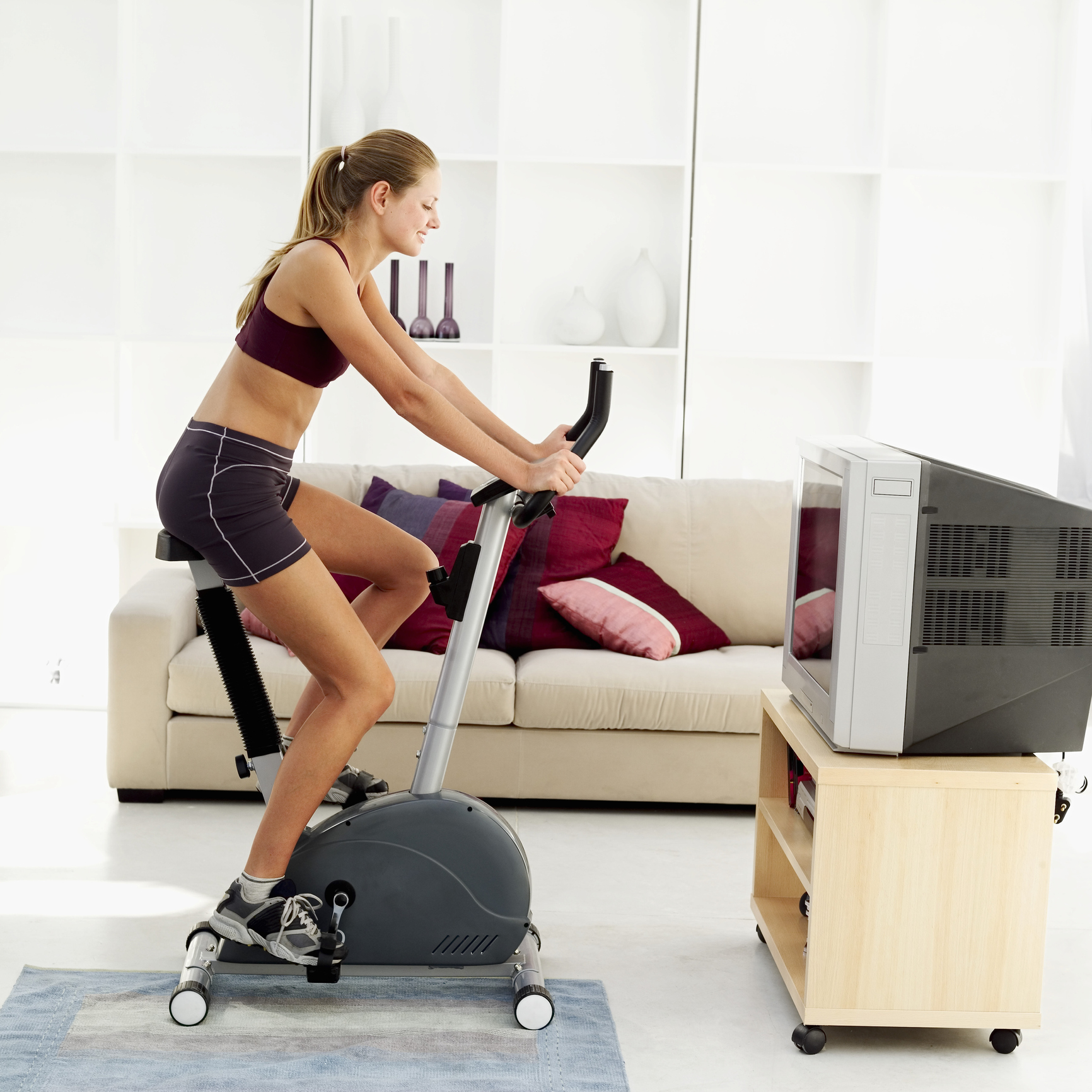 side view of a woman exercising on an exercise bicycle in her living room