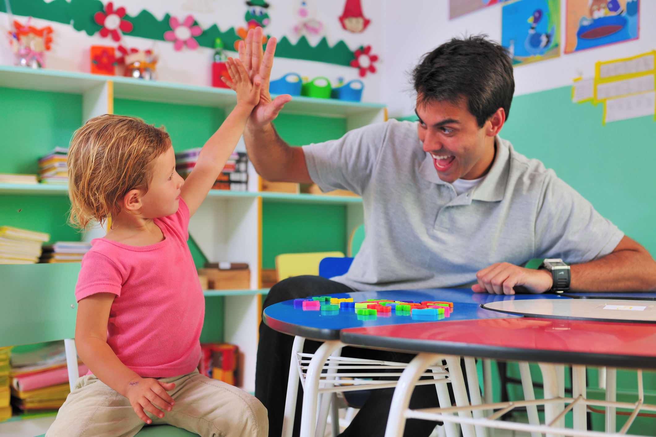 Preschool teacher and child giving a high-five