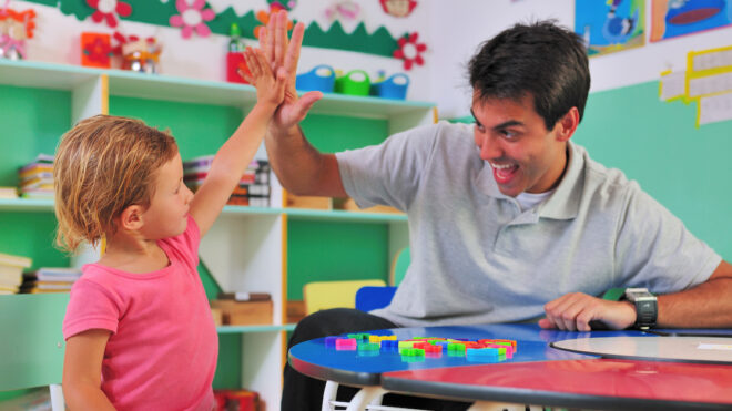 Preschool teacher and child giving a high-five