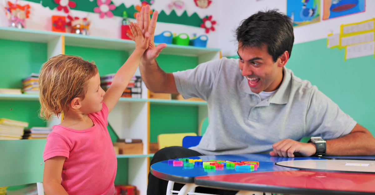 Preschool teacher and child giving a high-five