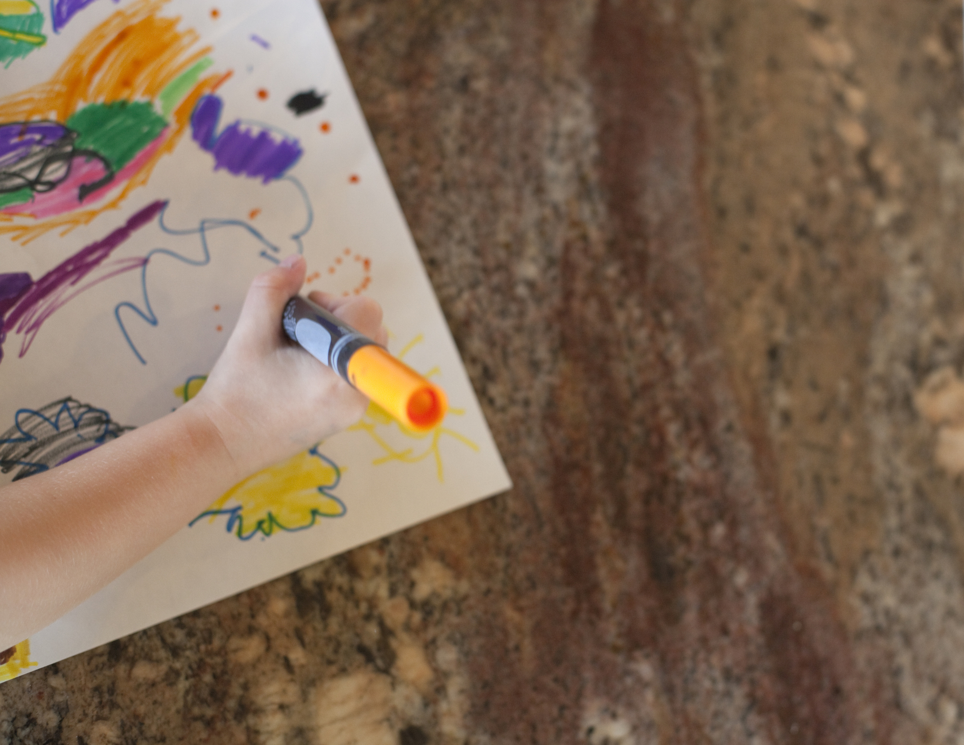 Girl drawing at kitchen counter, detail of hand