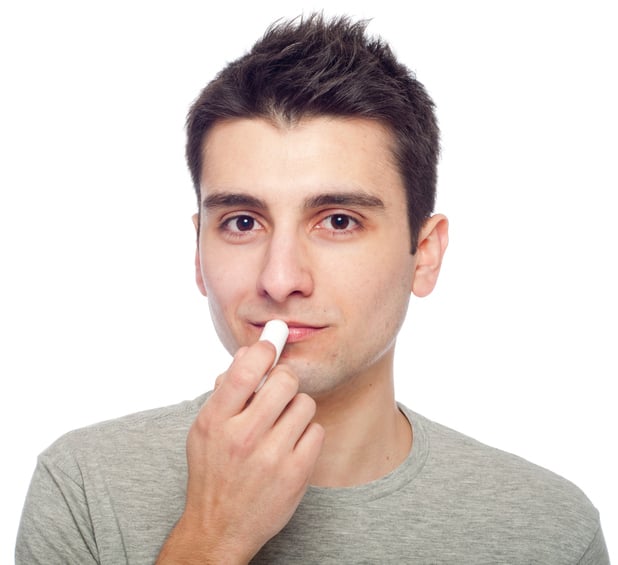 Young man applying lip balm