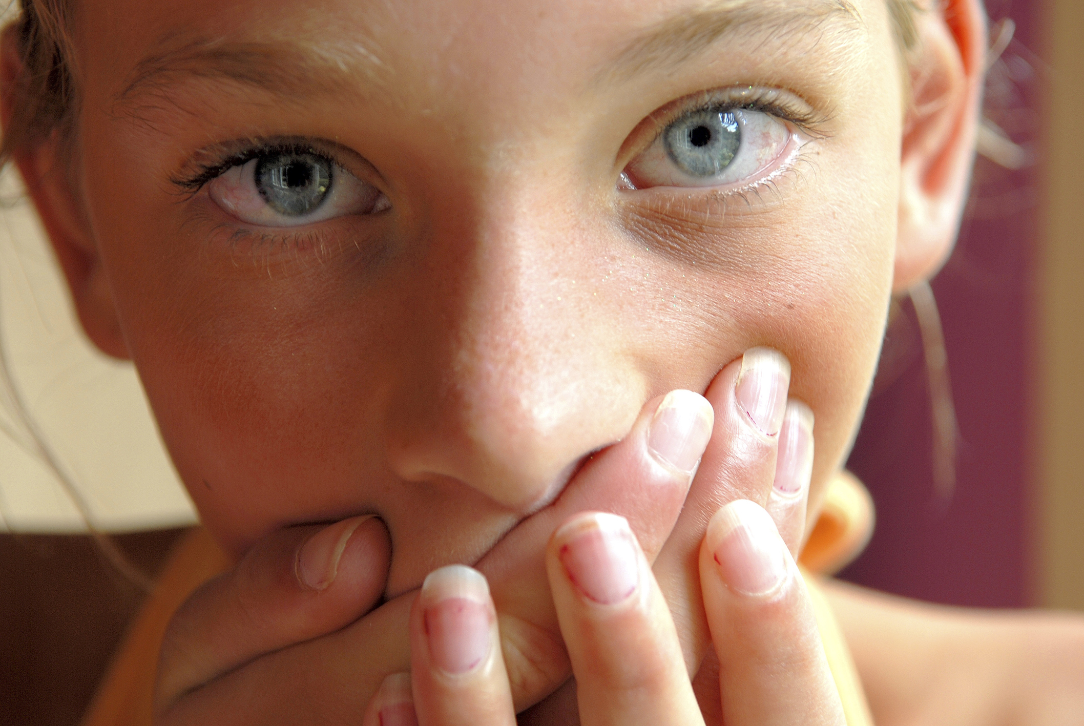 Close-up of a girl covering her mouth with her hands Close-up of a girl covering her mouth with her hands