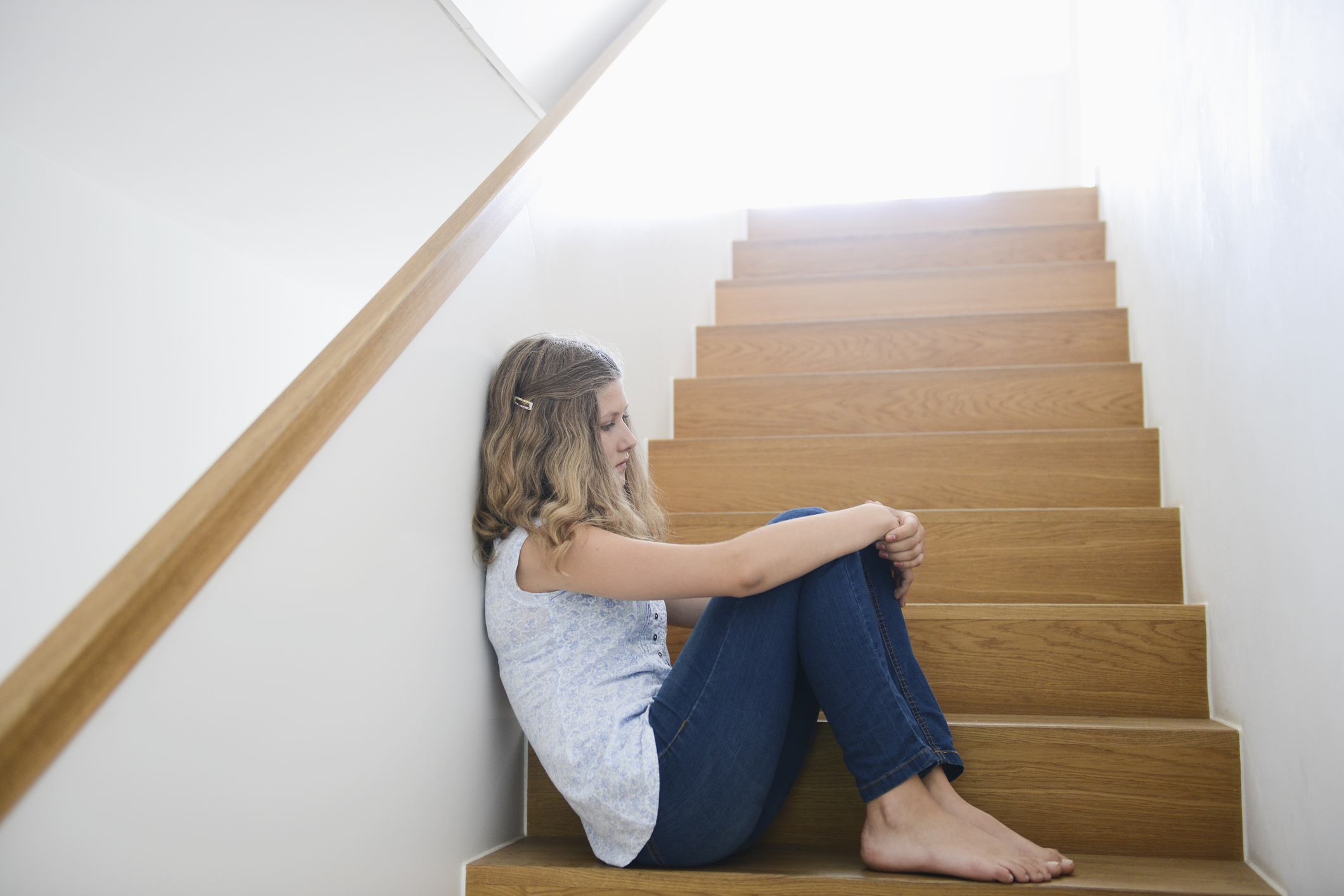 Girl sitting alone on wooden staircase