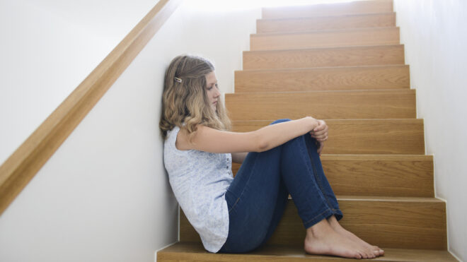 Girl sitting alone on wooden staircase