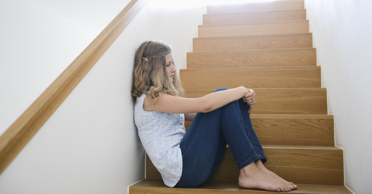 Girl sitting alone on wooden staircase