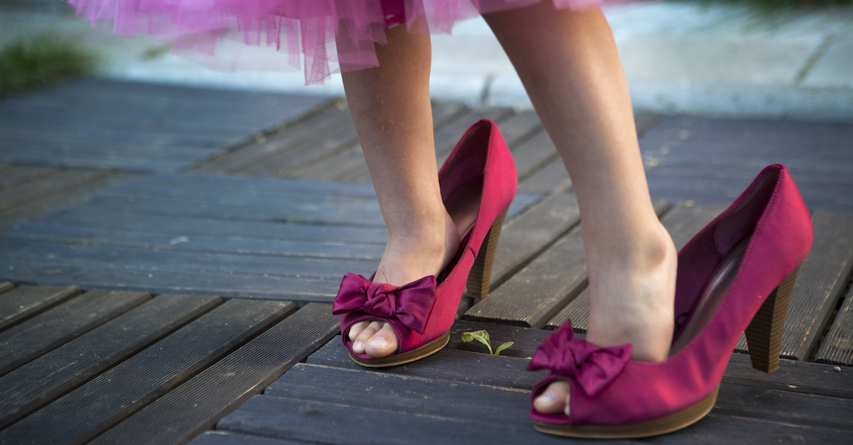 Little girl in her mother's high hells shoes