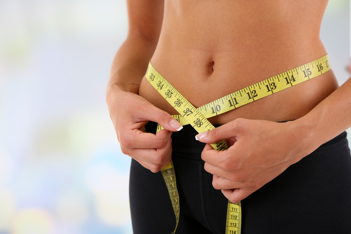 Woman measuring waist with tape measure