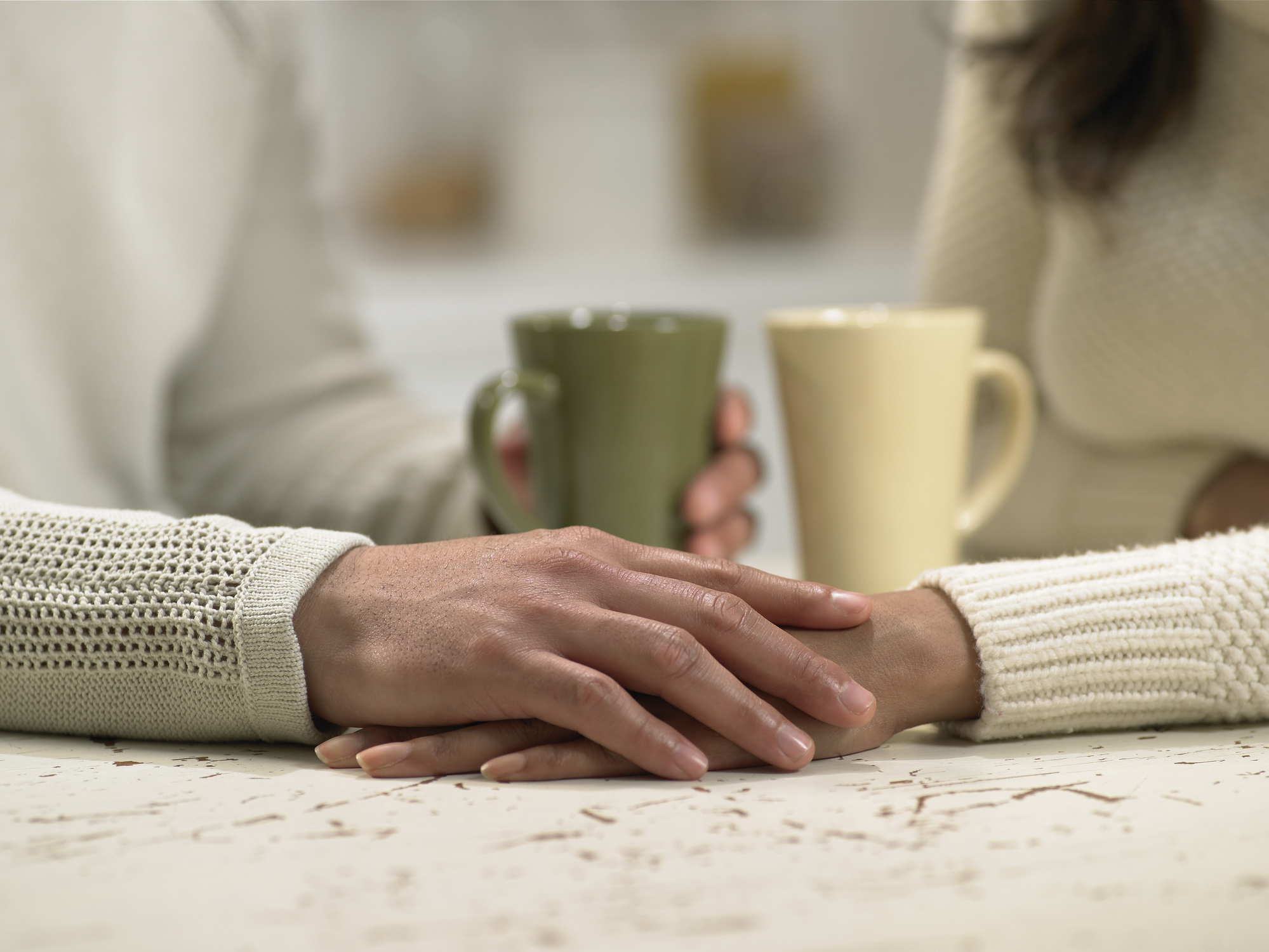 Couple holding hands across table, close-up