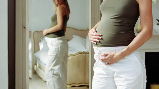 Pregnant woman looking at reflection in mirror