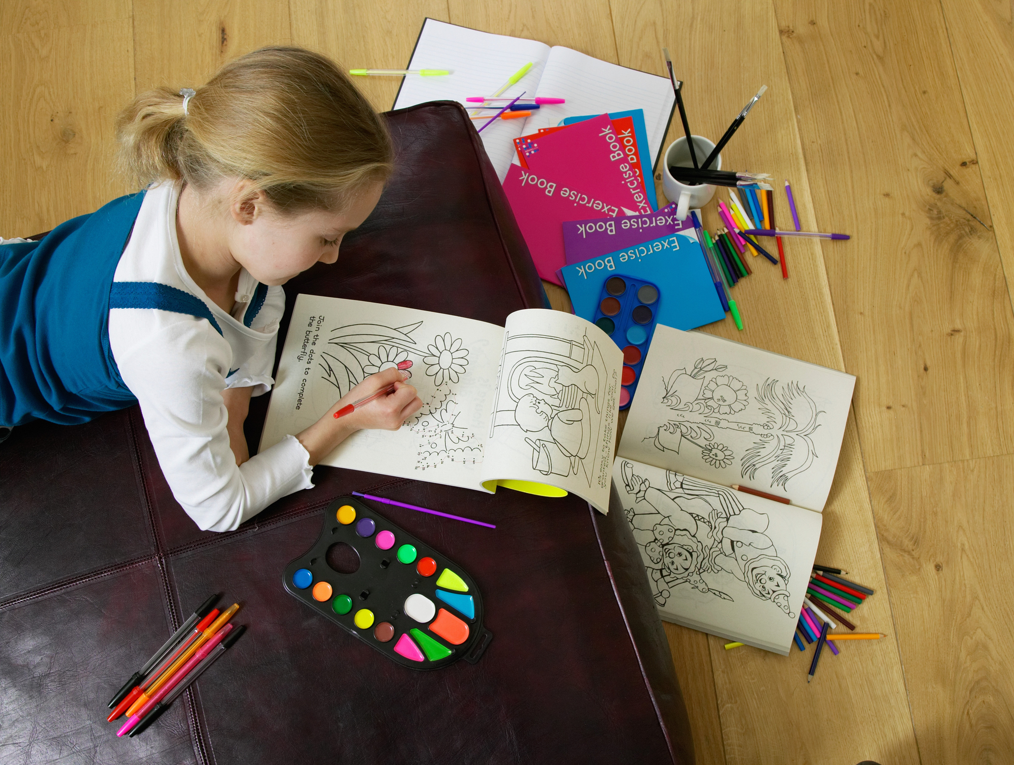 Girl (5-7) colouring in book, elevated view