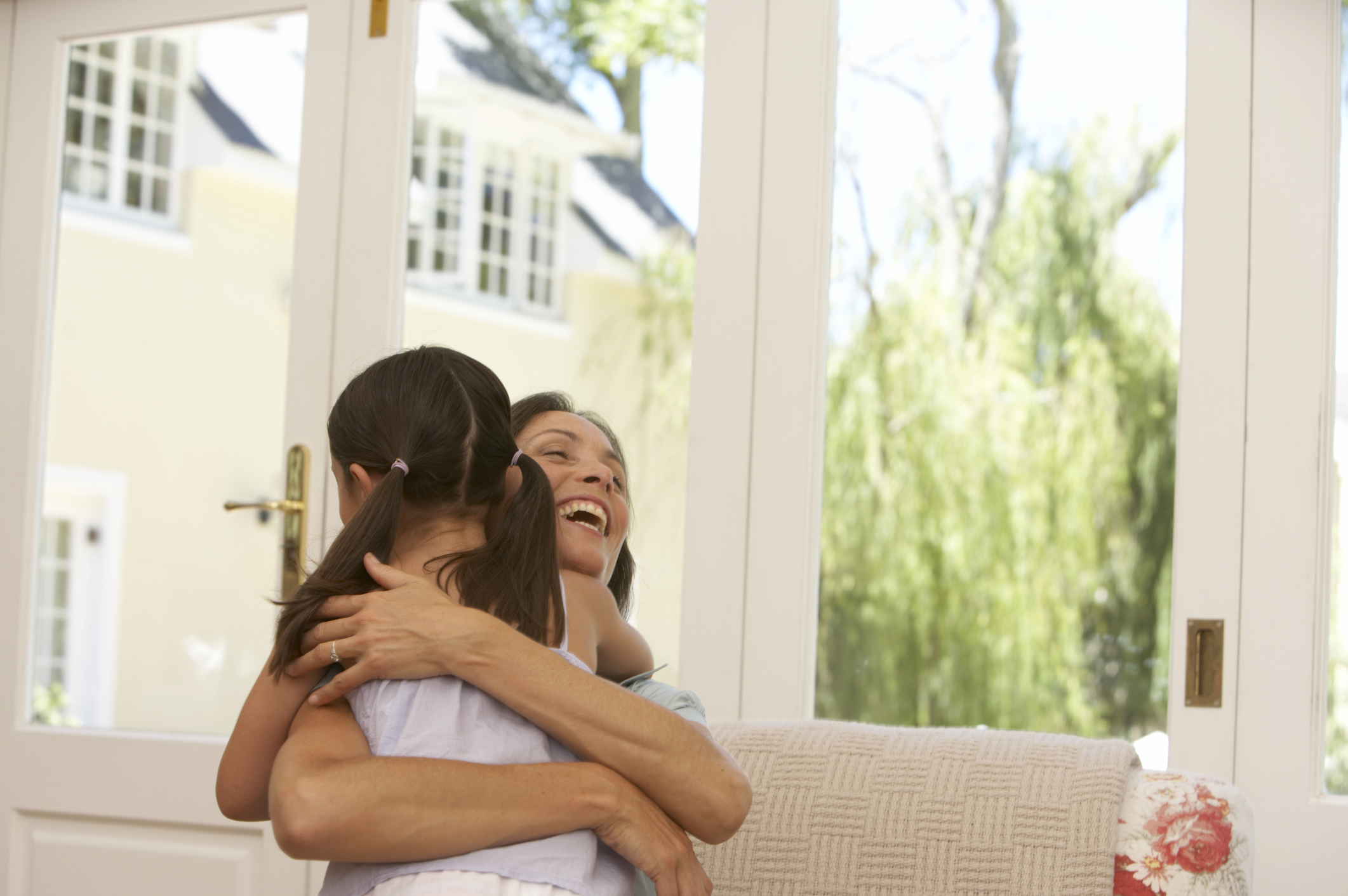 Mother embracing daughter (5-7) indoors, smiling