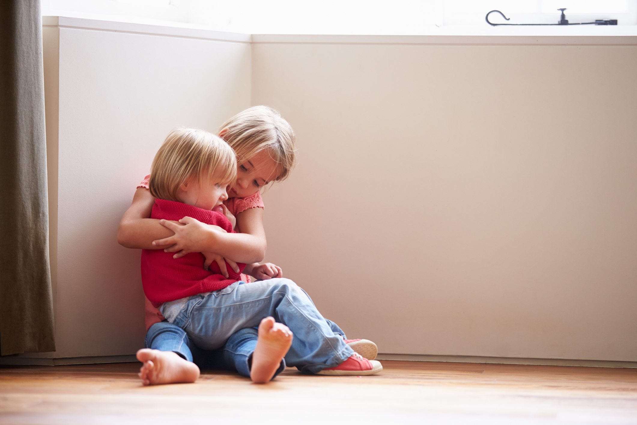 Unhappy Children Sitting On Floor In Corner At Home