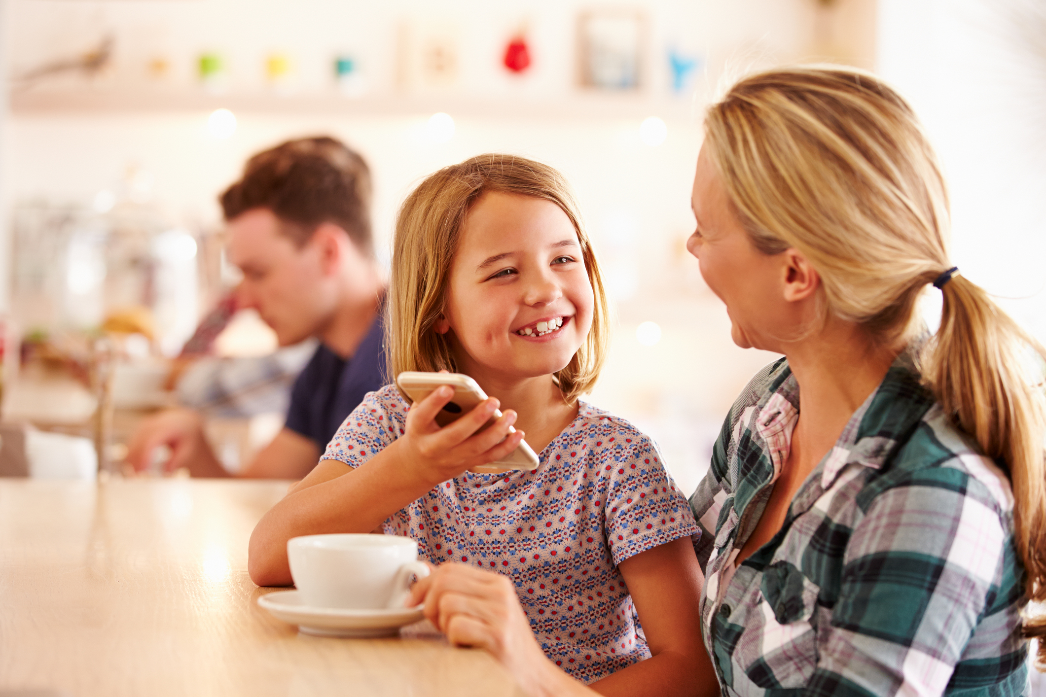 Mother and daughter in a cafe holding mobile phone