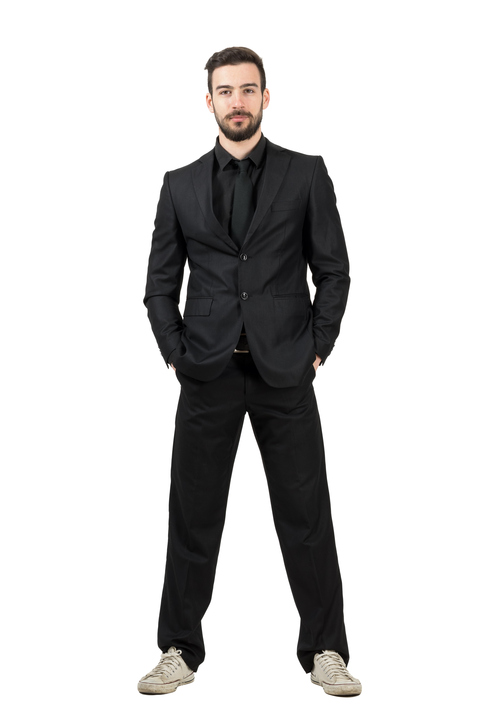 Bearded young businessman in white sneakers looking at camera