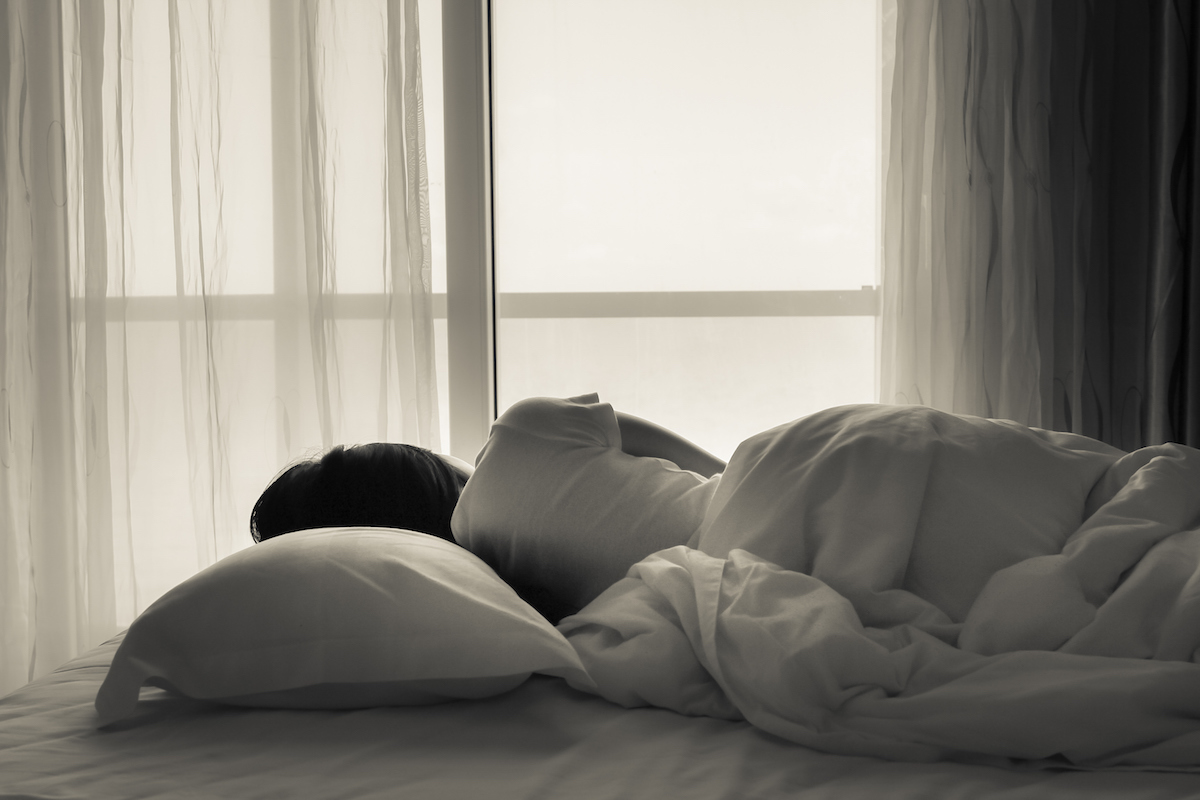 Young woman sleeping in bed beside the window
