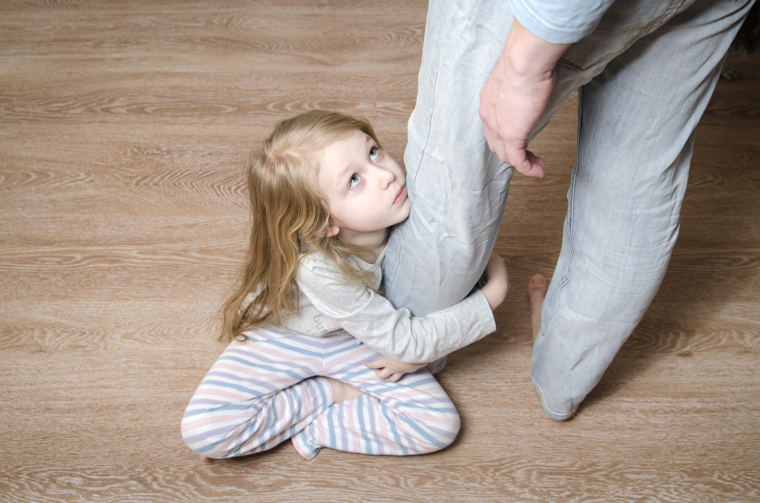 Young girl hugging her father's leg